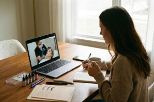 tela de notebook com videoaula de curso de micropigmentacao de sobrancelhas sendo assistida por mulher em casa